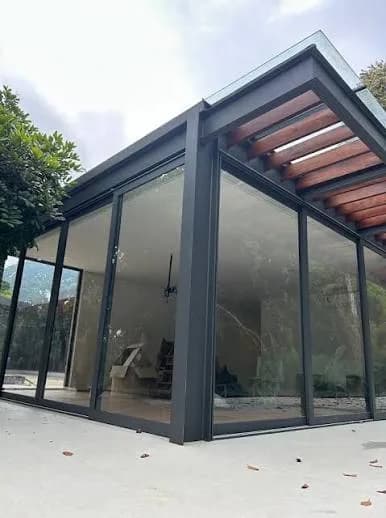 Ambiente fechado com esquadrias de alumínio grafite e vidro do piso ao teto