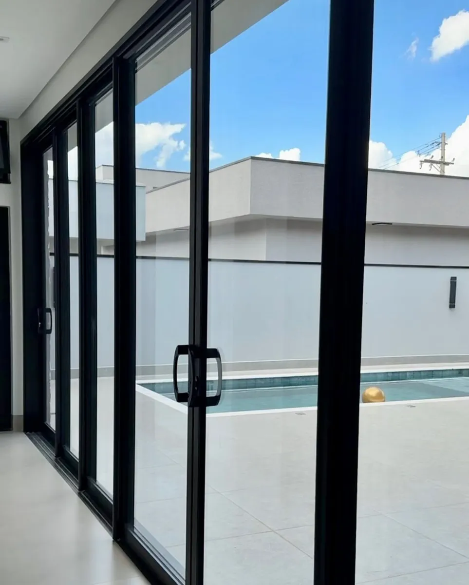 Porta de correr de 4 folhas em alumínio preto com vista para a piscina